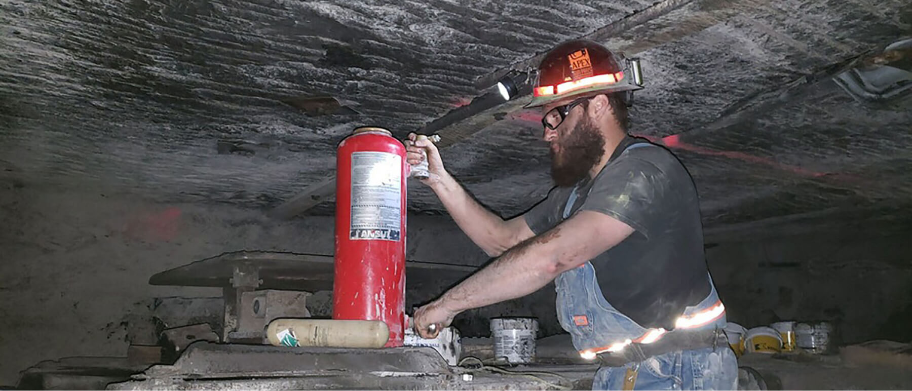 Man performing maintenance on a fire extinguisher in a mine