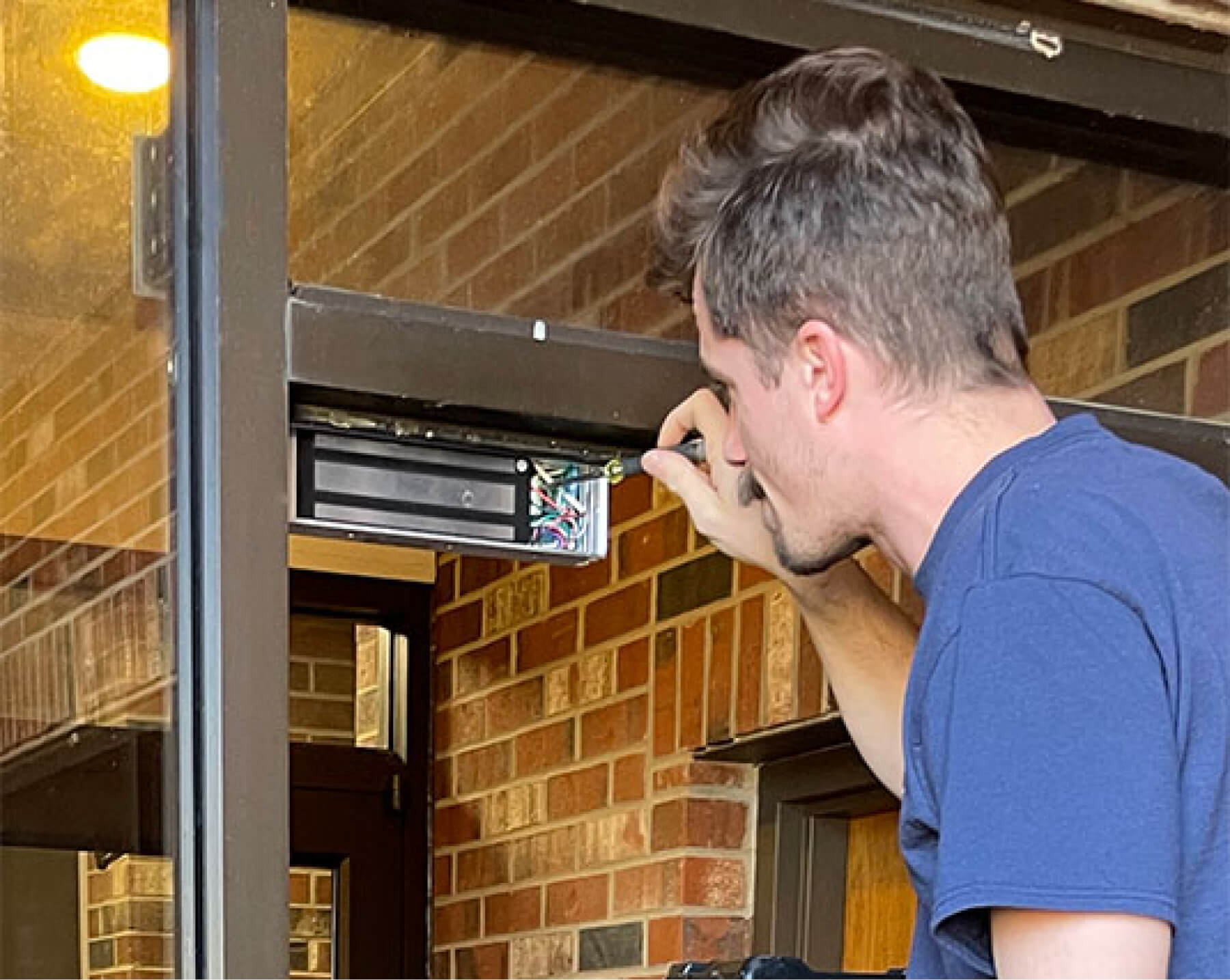 Marmic fire staffer performing maintenance on a door magnetic lock