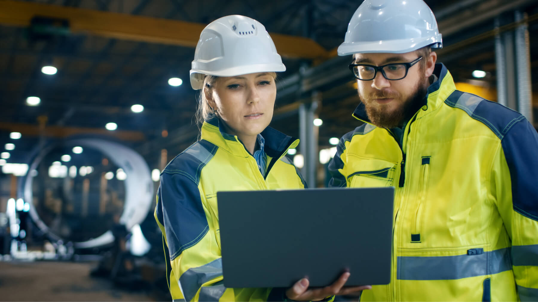 Man and woman in hardhats looking at a laptop